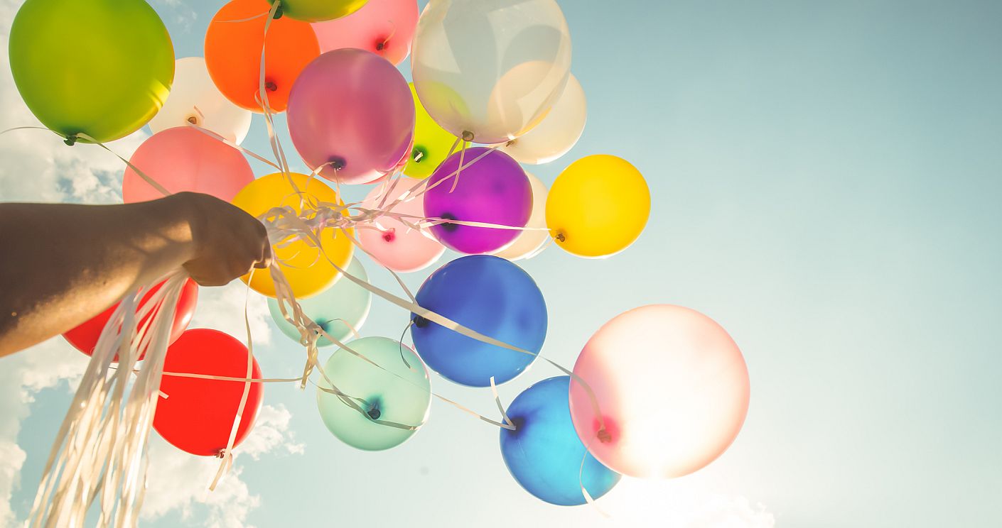 Bild von einer Hand, die bunte Luftballons in den Himmel hält. Dazu die Bildunterschrift: Die Werte der „Mutterkultur“ bilden die Richtschnur für lokale Freiheiten. © Getty Images/teppakorn tongboonto