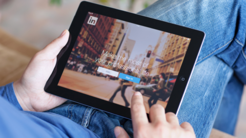 Mann hält iPad mit der App Linkedin auf dem Bildschirm. © Getty Images/Prykhodov