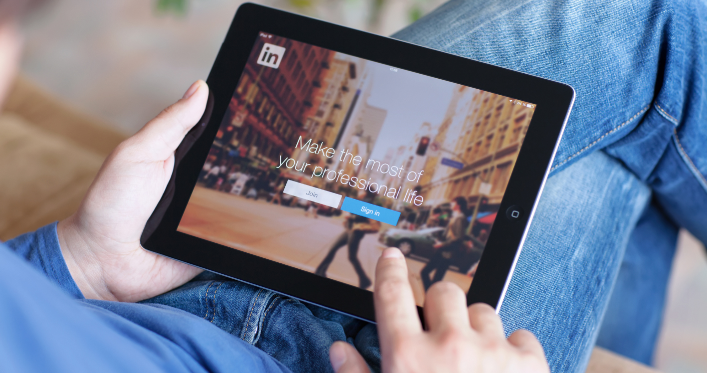 Mann hält iPad mit der App Linkedin auf dem Bildschirm. © Getty Images/Prykhodov