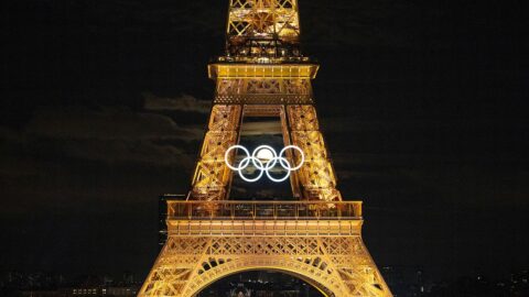 Der beleuchtete Eiffelturm während der Olympischen Spiele im Sommer 2024 in Paris (Frankreich). Am Turm sind erleuchtete Olympischen Ringe angebracht, hindurch leuchtet ein Vollmond. Dazu die Bildunterschrift: Die Olympischen Spiele in Paris lieferten starke Bild-Momente. Einmal stand der Mond so, dass er durch die Ringe am Eiffelturm schien. © IOC