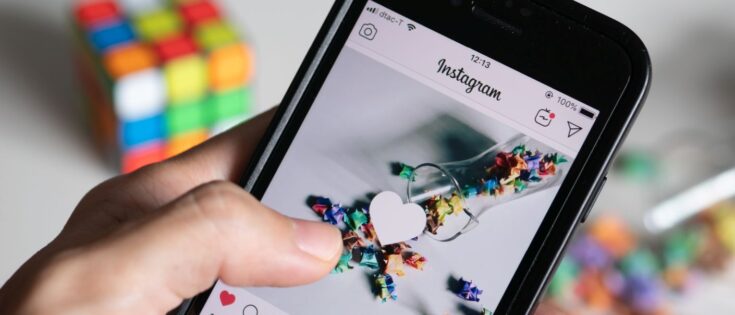 Eine Hand hält ein Smartphone, das eine Instagram-Seite mit einem Herz-Symbol für einen Like zeigt.