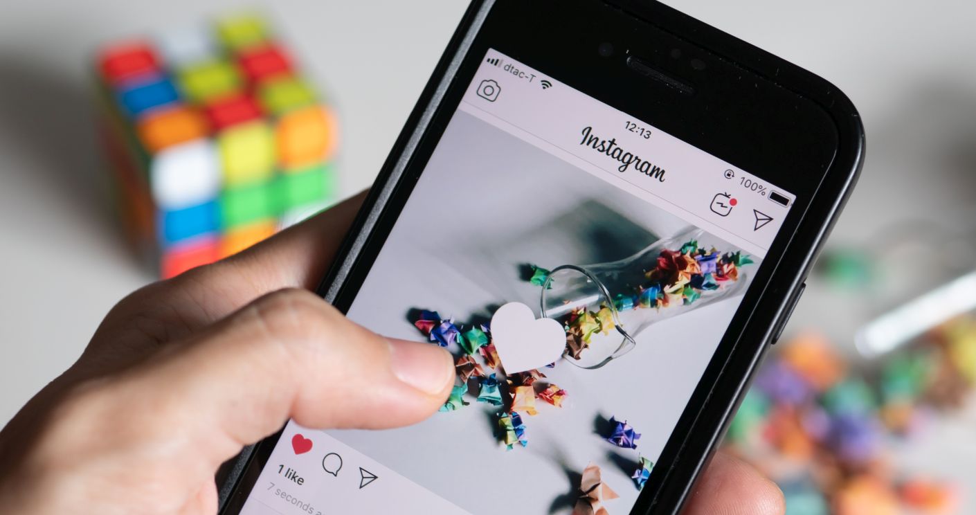 Eine Hand hält ein Smartphone, das eine Instagram-Seite mit einem Herz-Symbol für einen Like zeigt.