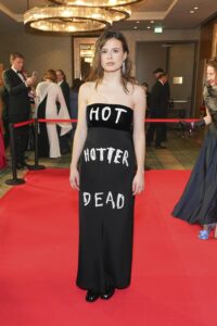 Luisa Neubauer in einem schwarzen Abendkleid mit der Aufschrift „HOT HOTTER DEAD“ auf dem roten Teppich beim Presseball im Januar 2024 in Berlin.