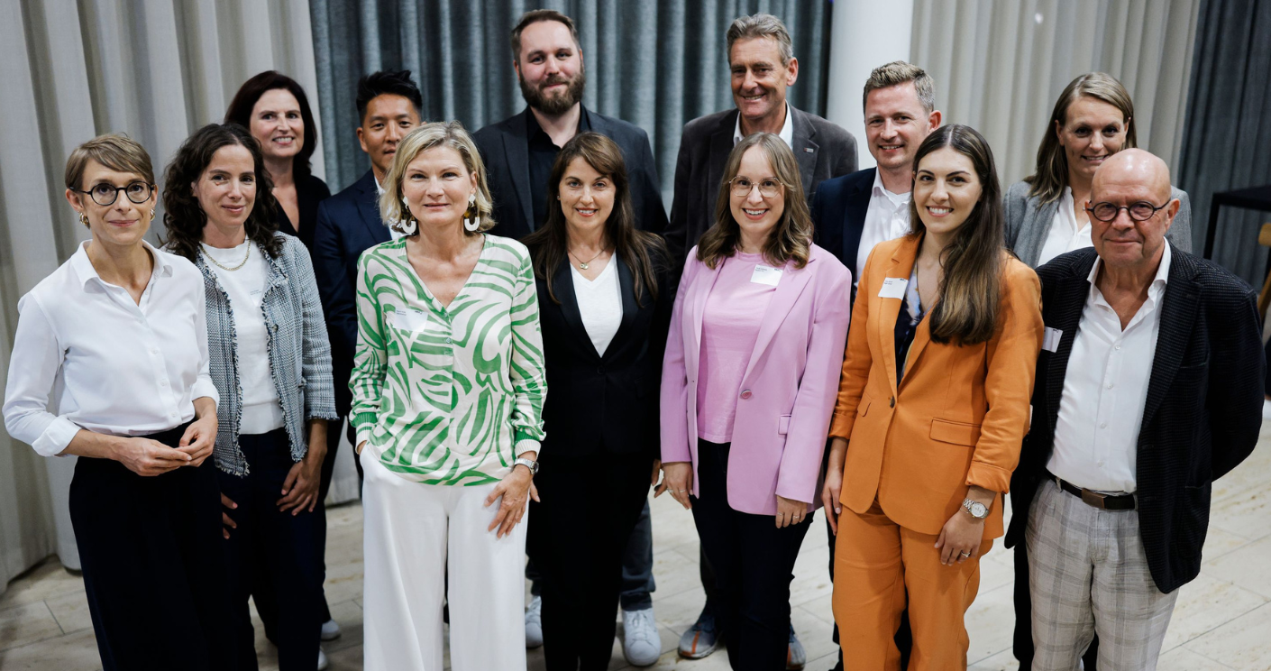 Gruppenfoto des BdKom-Präsidiums mit 13 Personen in formeller Kleidung, lächelnd vor einem neutralen Hintergrund.