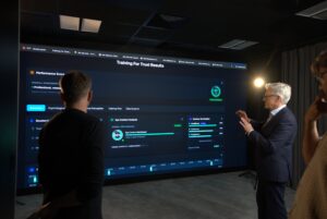 Zwei Personen, links Volker Thoms, rechts Andres Wittermann, stehen vor einem großen Bildschirm mit Datenanalysen und Grafiken.