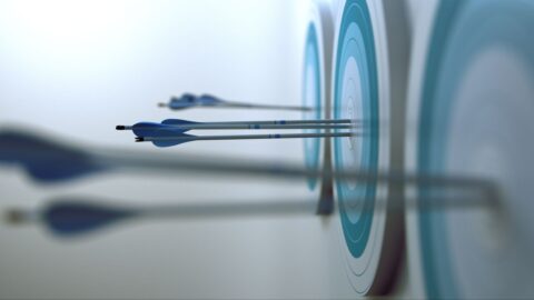 Drei Pfeile stecken in einem Ziel, das aus konzentrischen Kreisen in Blau- und Grautönen besteht.