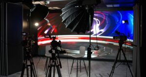 Professionelles TV-Studio mit Kameras, Scheinwerfern und einer beleuchteten LED-Wand.