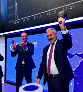 GEA-CEO läutet die Börsenglocke in Frankfurt, während ein Mann im Hintergrund applaudiert. Dax-Index sichtbar.
