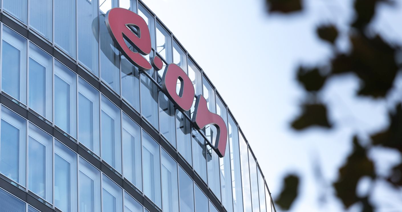 Modernes Bürogebäude mit dem roten Logo von e.on auf der Fassade, umgeben von einem klaren Himmel.