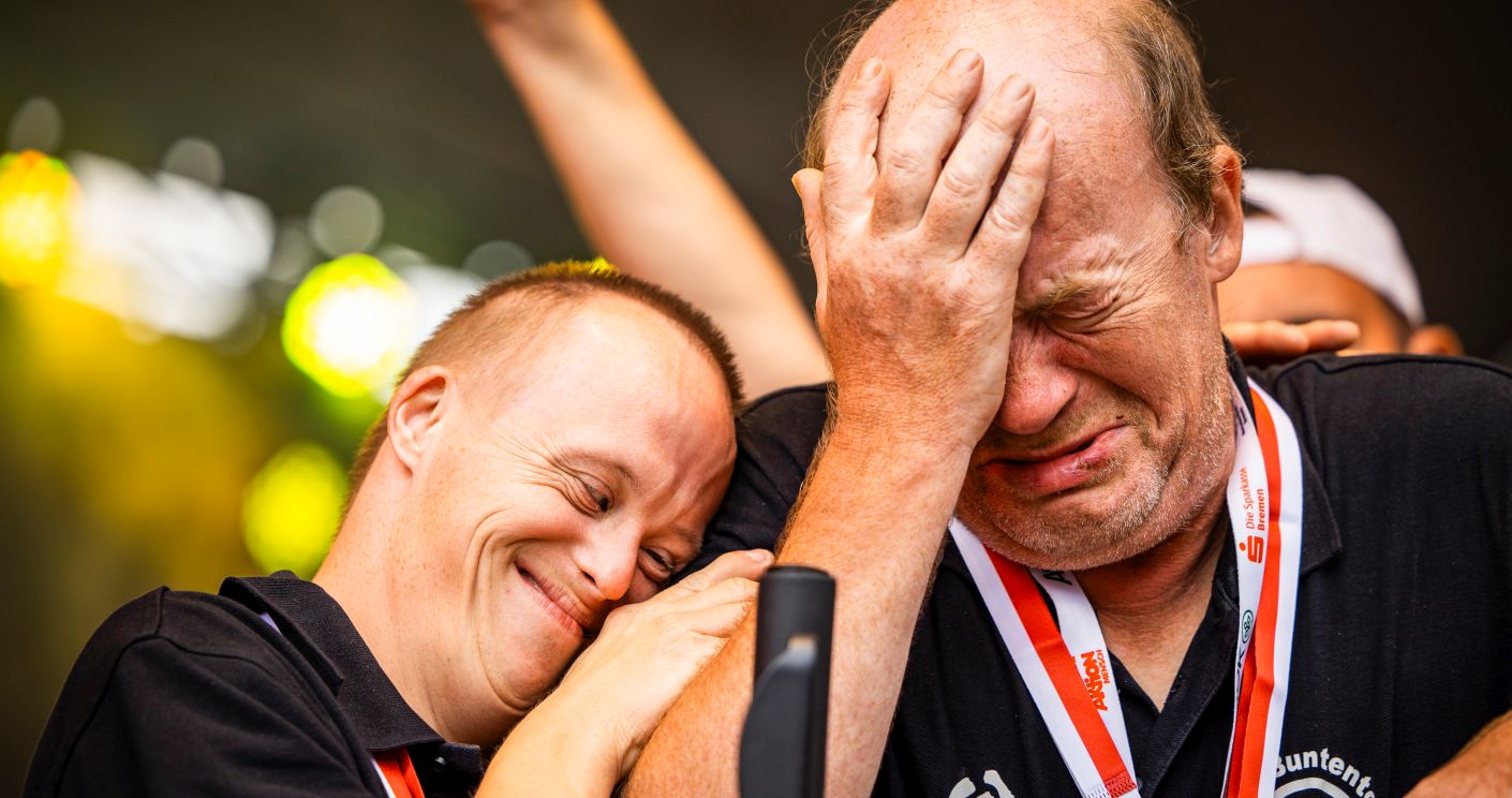Zwei Boccia-Teamkollegen umarmen sich während der Siegerehrung, einer weint vor Freude, der andere strahlt stolz.