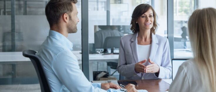 Meeting von drei Personen, zwei Frauen und einem Mann, in einem modernen Büro.