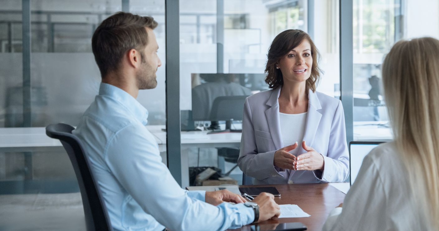 Meeting von drei Personen, zwei Frauen und einem Mann, in einem modernen Büro.