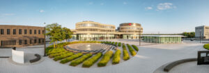 Außenansicht des Ernst Leitz Parks in Wetzlar mit modernem Gebäude und runder Leica-Zentrale im Hintergrund.