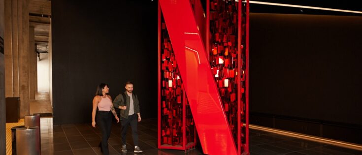 Zwei Personen gehen an einem großen, roten Netflix-Symbol in einem modernen Innenraum vorbei.