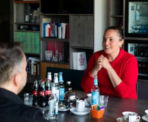 Eugenia Lagemann und Volker Thoms im Gespräch in einem Meetingraum, umgeben von Getränken und Gläsern auf dem Tisch.