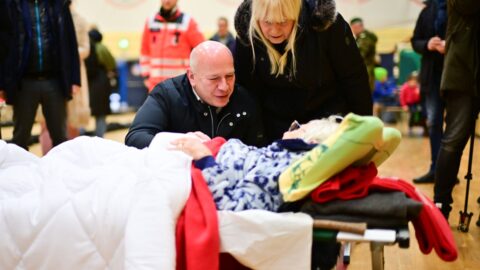 Kai Wegner und Iris Spranger sprechen mit der 97-jährigen Ingeborg in einer Notunterkunft während eines Stromausfalls.