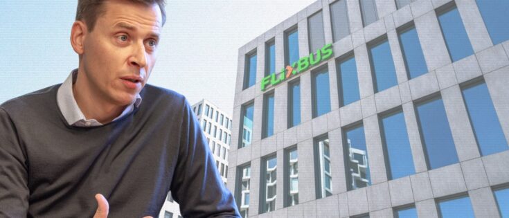 Mann im grauen Pullover spricht vor einem modernen Gebäude mit der Aufschrift "FLIXBUS" in grüner Schrift.