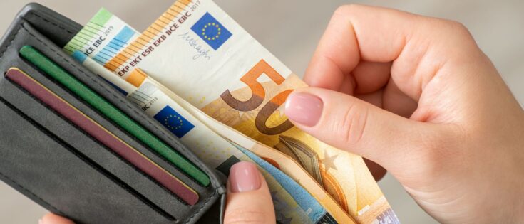 Nahaufnahme einer Frau, die Euro-Banknoten in ihrer Geldbörse zählt.