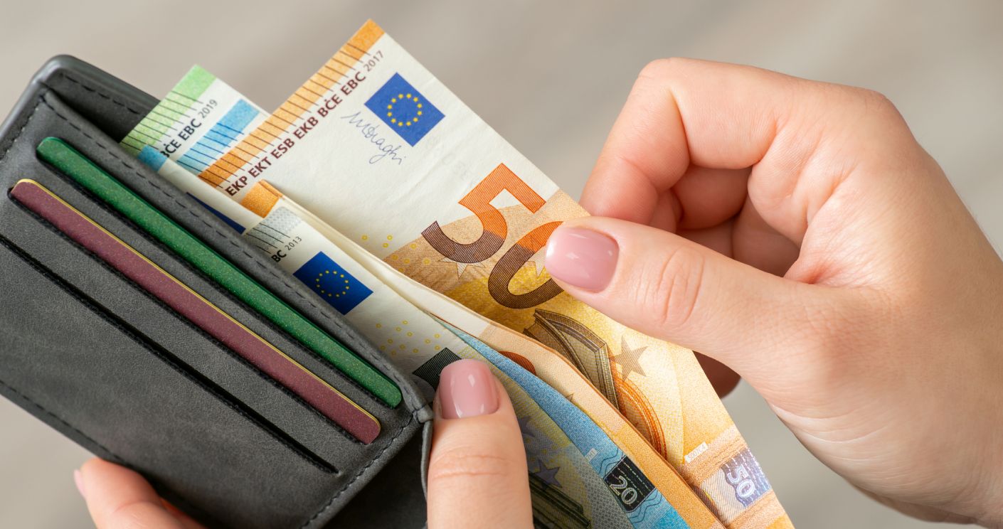 Nahaufnahme einer Frau, die Euro-Banknoten in ihrer Geldbörse zählt.