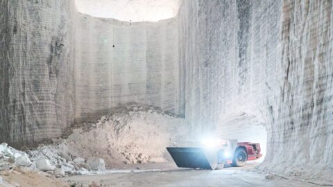 Radlader transportiert Salz in einer Abbauhalde, umgeben von hohen, hellen Salzwänden.