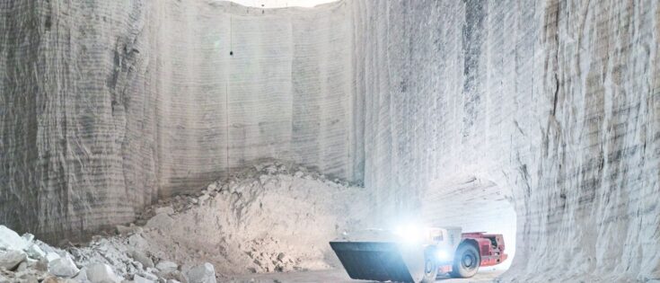Radlader transportiert Salz in einer Abbauhalde, umgeben von hohen, hellen Salzwänden.