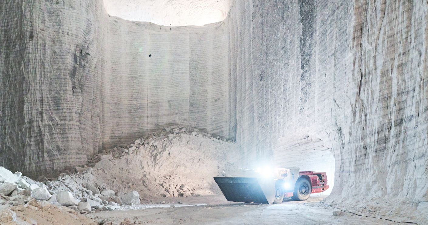 Radlader transportiert Salz in einer Abbauhalde, umgeben von hohen, hellen Salzwänden.