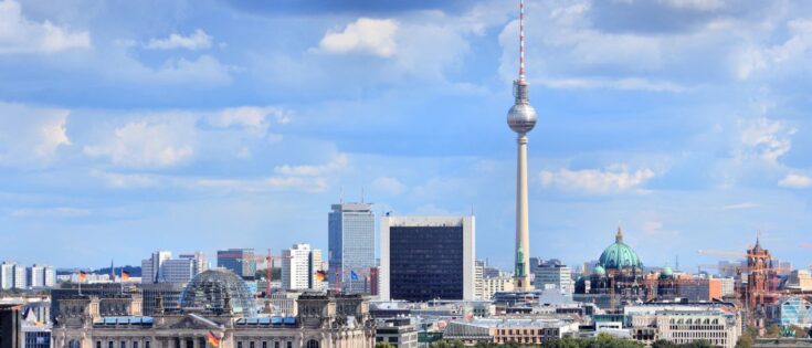 Skyline von Berlin mit dem Reichstag, Tiergarten und dem Fernsehturm vor einem bewölkten Himmel.