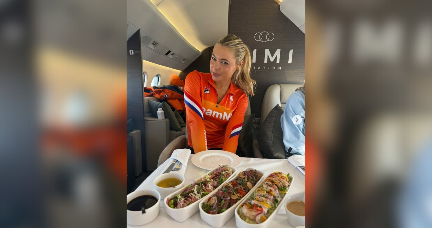 Frau in orangefarbener Sportkleidung sitzt in einem Flugzeug mit einem Tisch voller Sushi und Saucen.