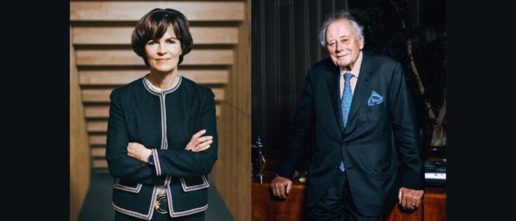 Porträt von zwei Personen: eine Frau mit verschränkten Armen und ein älterer Mann, beide in formeller Kleidung.