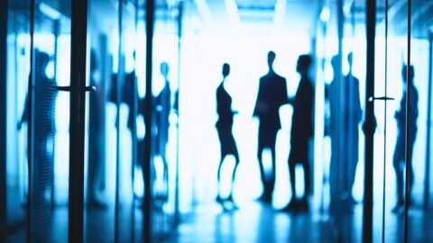 Silhouetten von Geschäftsleuten stehen in einem Corridor eines modernen Business Centers.