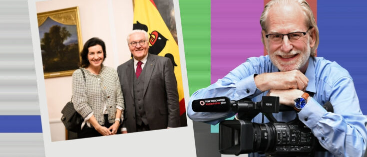 Souvenir-Foto mit zwei Personen, einer Frau und einem Mann, vor einem Gemälde und einer Fahne. Kamera im Vordergrund.