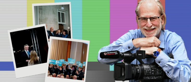 Ein lächelnder Mann mit Brille hält eine Kamera, umgeben von bunten Streifen und Polaroid-Bildern von Veranstaltungen.