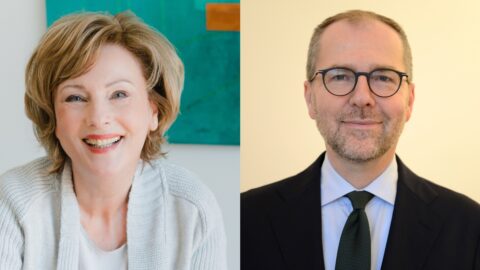 Porträt von zwei Personen, eine Frau mit lockigem Haar und ein Mann mit Brille, beide lächeln freundlich in die Kamera.