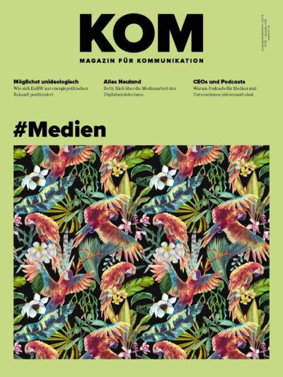 Cover of KOM Magazin für Kommunikation with lime background, oversized black 'KOM', three article teasers, and a colorful tropical floral border at the bottom.