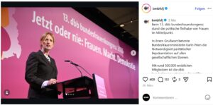 © Screenshot Instagram/@bmbfsfj | KOM - Magazin für Kommunikation Frau spricht am Rednerpult vor einer pinken Hintergrundwand mit dem Text „Jetzt oder nie: Frauen. Macht. Demokratie.“