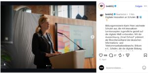 © Screenshot Instagram/@bmbfsfj | KOM - Magazin für Kommunikation Frau am Rednerpult bei einer Veranstaltung zur digitalen Bildung, im Hintergrund ein Bildschirm mit Präsentation.