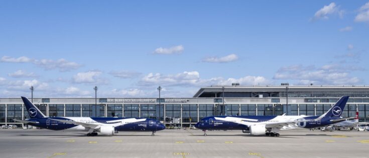 Zwei Lufthansa-Flugzeuge stehen vor dem Flughafen BER unter blauem Himmel, um 100 Jahre Airline zu feiern.