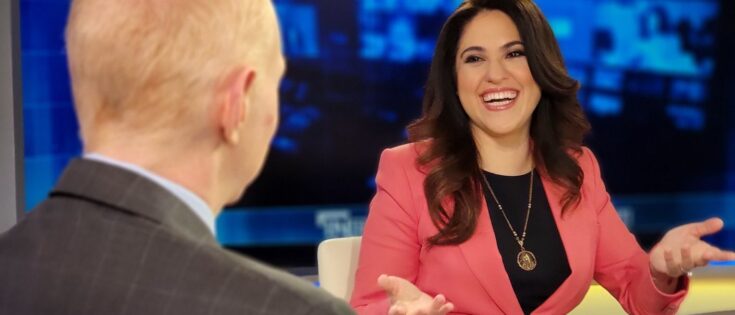 Montse Alvarado lächelt und spricht in einem Studio, während ein Gesprächspartner ihr gegenüber sitzt.
