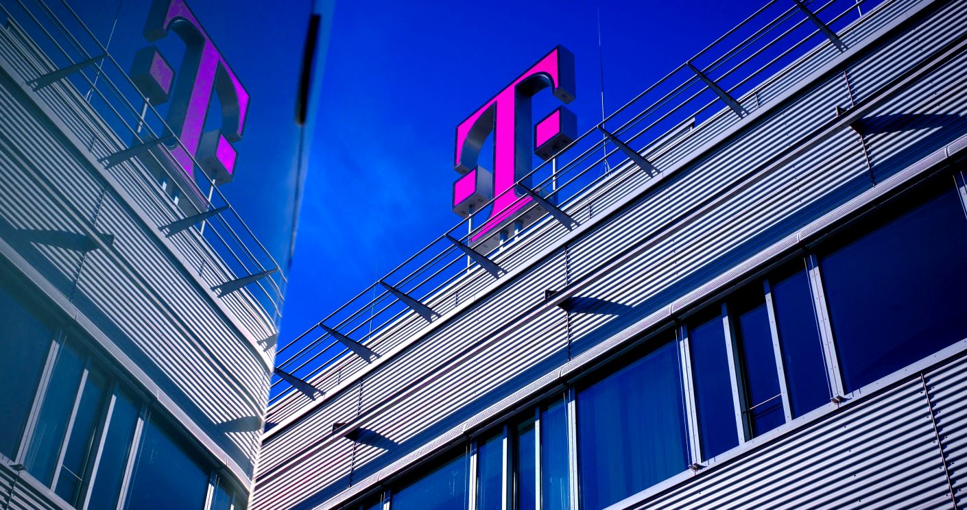 Nahaufnahme von einem Bürogebäude mit großem pinken Telekom-Logo vor blauem Himmel.