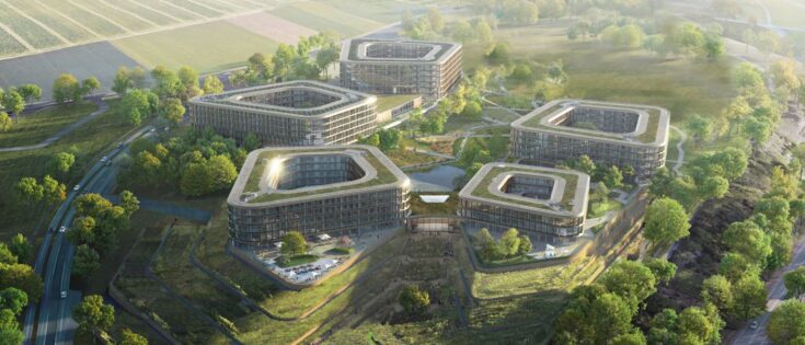 Moderne Gebäude in einer grünen Landschaft, umgeben von Feldern und Bäumen, mit sanften Hügeln im Hintergrund.
