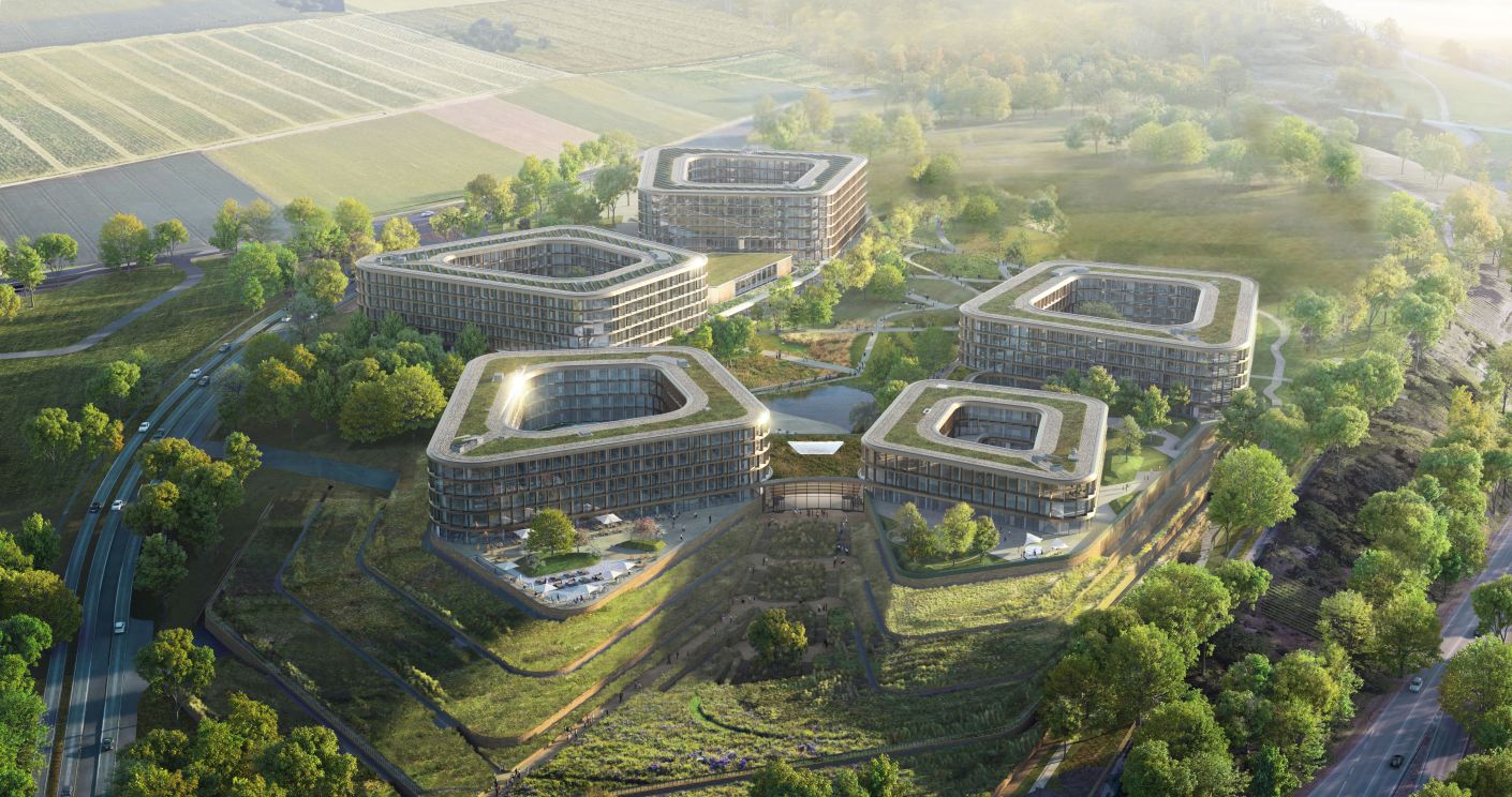 Moderne Gebäude in einer grünen Landschaft, umgeben von Feldern und Bäumen, mit sanften Hügeln im Hintergrund.
