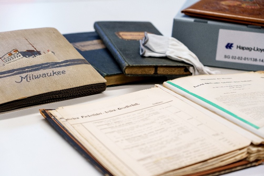 Historische Bücher und Dokumente, darunter ein Notizbuch mit dem Titel "Milwaukee", auf einem Tisch angeordnet.