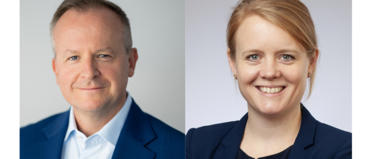 Zwei Personen in Anzügen, lächelnd, vor neutralem Hintergrund; links ein Mann, rechts eine Frau.