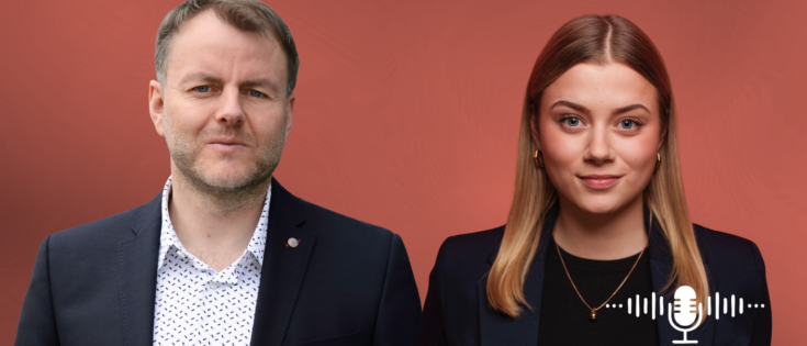 Zwei Personen stehen vor einem roten Hintergrund, links ein Mann in Anzug, rechts eine Frau in Blazer, Mikrofon-Icon rechts.