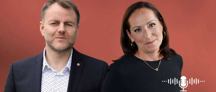 Volker Thomas und Monika Schaller stehen vor einem roten Hintergrund, beide in formeller Kleidung, mit Mikrofon-Icon.