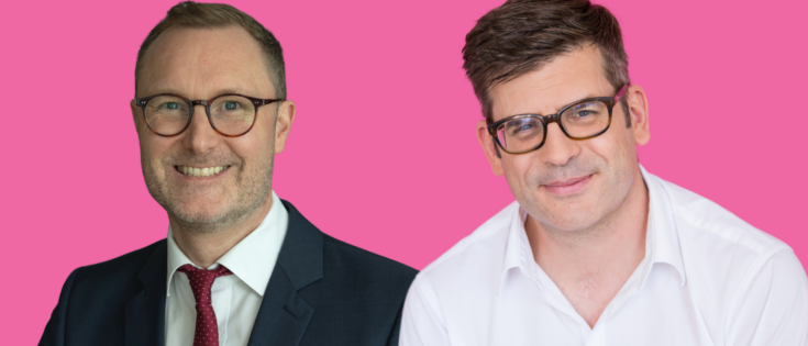 Zwei Männer in Anzügen vor pinkem Hintergrund, lächelnd, einer mit Brille, der andere mit Hemd.